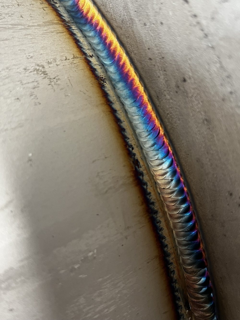Heat-tinted TIG weld running along a stainless vessel